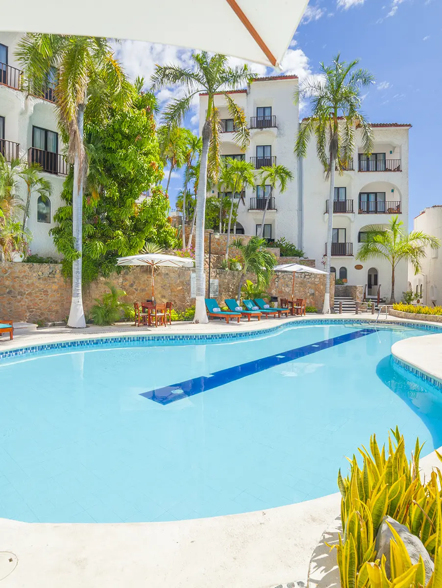 Área de albercas del Hotel Marina Resort con camastros y jardines